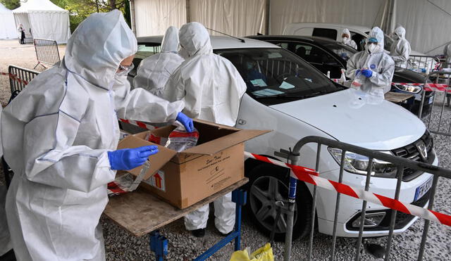 Firefighters and members of the French Red-Cross wearing protective suits perform tests and handle samples at a drive-through Covid-19 screening site on October 14, 2020 in Montpellier. - Faced with the resurgence of the epidemic in France, President Emmanuel Macron is expected to announce on October 14 evening new restrictive measures, even possible curfews, which should especially affect major cities where Covid-19 is running amok. (Photo by Pascal GUYOT / AFP)