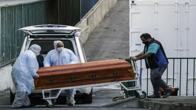 Employees of a funeral parlour carry the coffin of a COVID-19 victim into a vehicle, outside the Carlos Van Buren Hospital in Valparaiso on June 12, 2020. - Chile registered the worst daily figures so far in the current coronavirus pandemic on Friday, with 6,754 new infections in the last 24 hours and 222 more deaths, totaling up to now 2,870 fatalities, local authorities reported. (Photo by ADRIANA THOMASA CARBALLO / AFP)