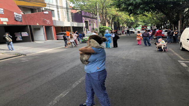 People and their pets are seen on a street during a quake in Mexico City, on June 23, 2020. - A 7.1 magnitude quake was registered Tuesday in the south of Mexico, according to the Mexican National Seismological Service. (Photo by Pedro PARDO / AFP)