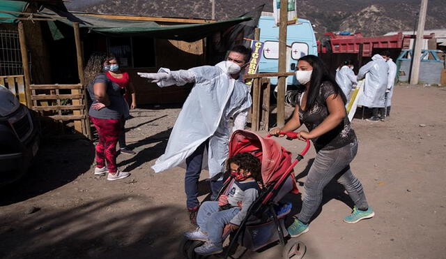 Trabajadores de la organización TECHO-Chile prestando asistencia sanitaria en la comuna de Puente Alto, en Santiago. Foto: EFE