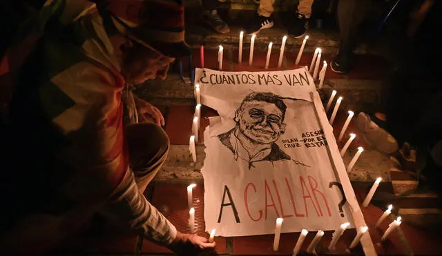A man lights a candle around a poster reading "How many more are you going to silence?" and depicting Dilan Cruz, a young demonstrator who had been wounded by a member of the Mobile Anti-Disturbance Squadron (ESMAD) during a protest against the Colombian government and died yesterday, during a vigil in Cali, Colombia, on November 26, 2019. - Under-fire Colombian President Ivan Duque will meet with protest leaders on Tuesday, a minister announced, after five consecutive days of anti-government protests. The meeting will form part of the national dialogue Duque launched on Sunday to address corruption, economic inequality and other woes. (Photo by LUIS ROBAYO / AFP)