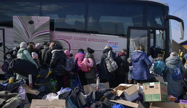Ucranianos hacen cola para tomar un autobús directo a Italia después de cruzar la frontera hacia Polonia. Foto: referencial/AFP