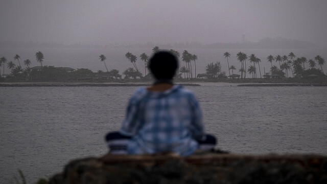 A woman meditates as a vast cloud of Sahara dust is blanketing the city of San Juan, Puerto Rico on June 22, 2020. - An expansive plume of dust from the Sahara is traveling westward across the Atlantic Ocean and is expected to reach the Caribbean and parts of the United States later this week. (Photo by Ricardo ARDUENGO / AFP)