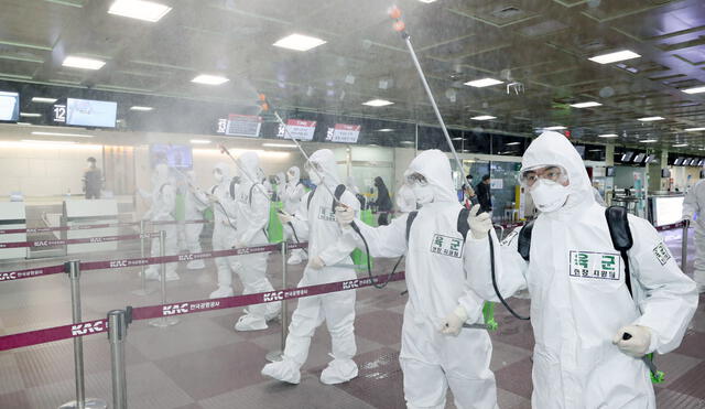Soldados surcoreanos que usan desinfectante en aerosol de equipo de protección para ayudar a prevenir la propagación del coronavirus COVID-19, en el Aeropuerto Internacional de Daegu en Daegu.