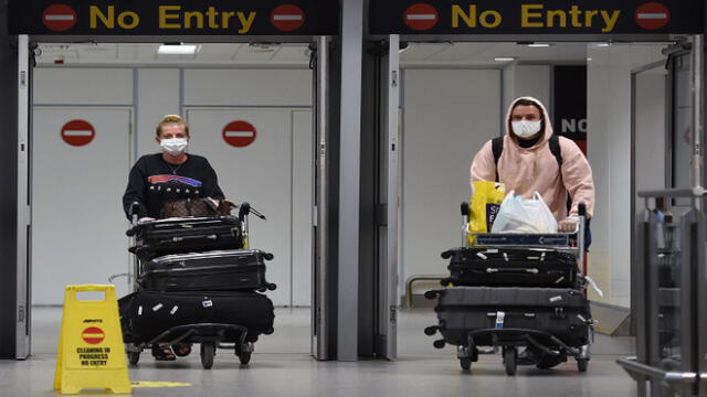 Passengers wearing PPE (personal protective equipment), including a face mask as a precautionary measure against COVID-19, arrive at Terminal 1 of Manchester Airport in northern England, on June 8, 2020, as the UK government's planned 14-day quarantine for international arrivals to limit the spread of the novel coronavirus begins. (Photo by Oli SCARFF / AFP)