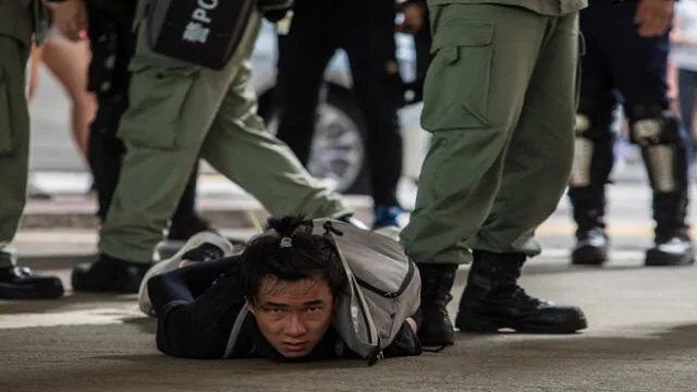 Riot police detain a man as they clear protesters taking part in a rally against a new national security law in Hong Kong on July 1, 2020, on the 23rd anniversary of the city's handover from Britain to China. - Hong Kong police made the first arrests under Beijing's new national security law on July 1 as the city greeted the anniversary of its handover to China with protesters fleeing water cannon. (Photo by DALE DE LA REY / AFP)