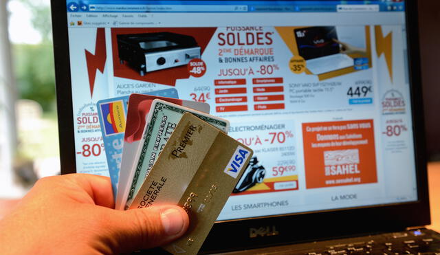 A person shows credit cards in front of a computer screen displaying electronics goods on sale on July 8, 2014 in Lille. AFP PHOTO / DENIS CHARLET (Photo by DENIS CHARLET / AFP)