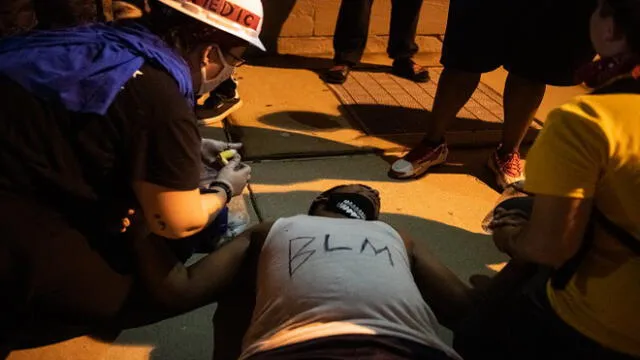 KENOSHA, WI - AUGUST 25: A demonstrator passes out during a clash with law enforcement on August 25, 2020 in Kenosha, Wisconsin. As the city declared a state of emergency curfew, a third night of civil unrest occurred after the shooting of Jacob Blake, 29, on August 23. Video shot of the incident appears to show Blake shot multiple times in the back by Wisconsin police officers while attempting to enter the drivers side of a vehicle. The 29-year-old Blake was undergoing surgery for a severed spinal cord, shattered vertebrae and severe damage to organs, according to the family attorneys in published accounts.   Brandon Bell/Getty Images/AFP