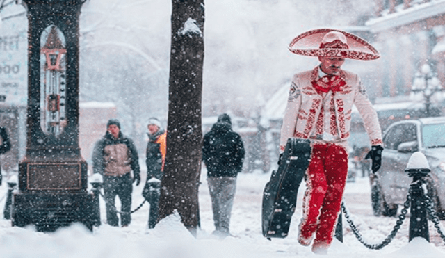 La fotografía tomada por Cameron Frazier captura a un mariachi cuyo atuendo color rojo contrasta con la blanca nieve mientras carga su guitarra.