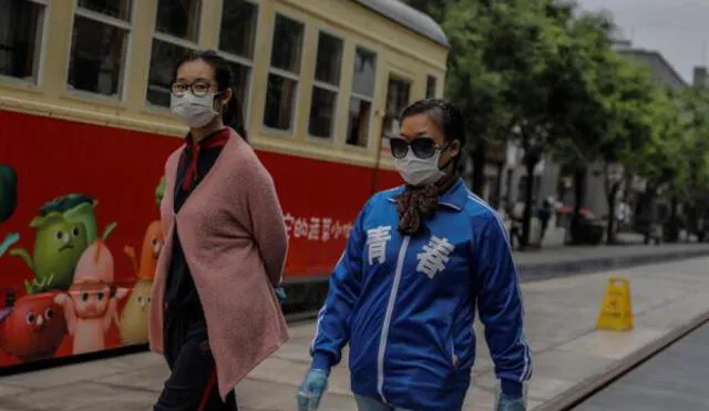Mujeres caminan por la calle con guantes y mascarillas. Foto: EFE.