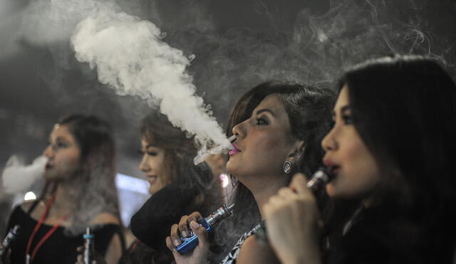 Promoters smoke electronic cigarettes during the VapeFair in Kuala Lumpur on December 5, 2015. Vaping is an alternative to smoke by inhaling water vapour through a vapouriser utilised Propylene Glycol or Vegetable Glycerin based liquid, mixed with small amounts of nicotine and food grade flavoring that then get vaporized in a small battery powered atomizer. AFP PHOTO / MOHD RASFAN (Photo by Mohd RASFAN / AFP)