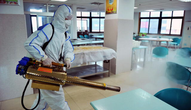 Un voluntario de la Cruz Roja participa en labores de desinfección de un edificio en Qingdao, provincia de Shandong (China).