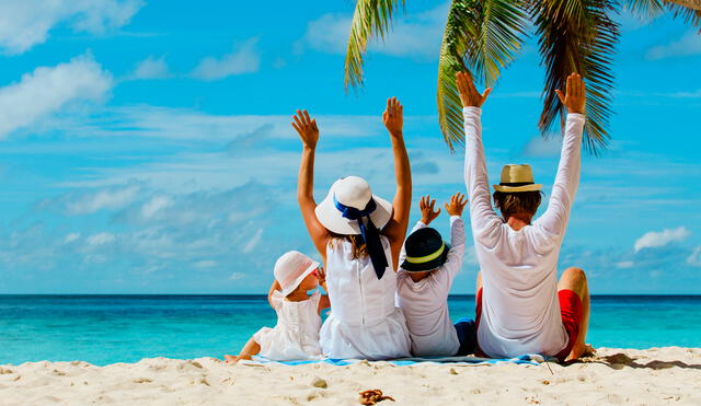 happy family with two kids hands up on tropical beach