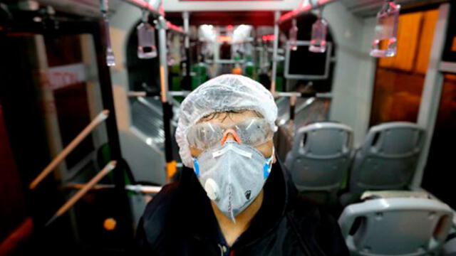 Un trabajador del municipio de Teherán limpia un autobús para evitar la propagación de la enfermedad COVID-19. Foto: AFP.