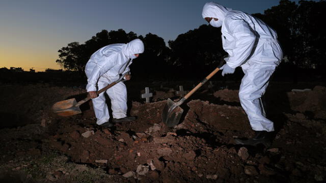 Cemetery workers wearing protective clothing bury a victim of COVID-19 at the Sao Franciso Xavier cemetery in Rio de Janeiro, Brazil, on May 29, 2020. (Photo by CARL DE SOUZA / AFP)