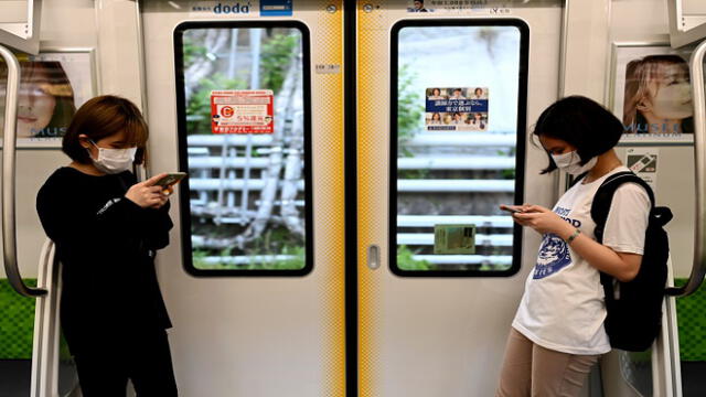 People wearing face masks amid concerns over spread of coronavirus (COVID-19) ride a train in Tokyo on Mau 24, 2020. - Prime Minister Shinzo Abe on May 21, 2020 lifted a state of emergency in several big cities in western Japan and hinted that the measure would be removed nationwide -- Tokyo and its neighbouring regions -- as early as next week. (Photo by Behrouz MEHRI / AFP)