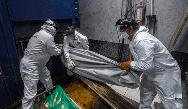 Empleados del panteón Iztapalapa ingresan los restos de una víctima por COVID-19 a un horno en el crematorio. Foto: AFP/Pedro Pardo