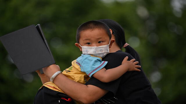 A mother holds his son next to Yangtze River in Wuhan, in China�s central Hubei province on May 12, 2020. - Wuhan plans to conduct coronavirus tests on the Chinese city's entire population after new cases emerged for the first time in weeks in the cradle of the global pandemic, state media reported on May 12. (Photo by Hector RETAMAL / AFP)