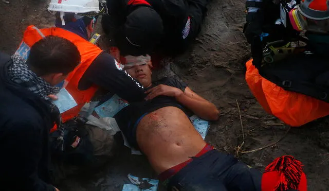 Equipos de emergencia trasladan a un manifestante que se encuentra inconsciente luego de caer en el río Mapocho. Foto: EFE