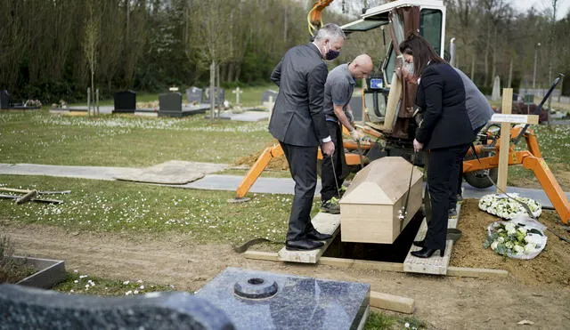 Employees of the Bouvy funeral house wear face masks as a protective measure while they burry a person who died of the COVID-19 at the cemetery of Kraainem on April 8, 2020 in Brussels as the deceased person's relatives were unable to attend the ceremony for sanitary reasons. (Photo by Kenzo TRIBOUILLARD / AFP)