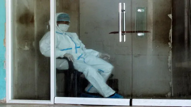 A man wearing personal protective equipment (PPE) rests at the entrance of the emergency room of the University Hospital in Maracaibo, Zulia State, Venezuela, on July 2, 2020, amid the COVID-19 coronavirus pandemic. - The flea market -closed since May 24- was a focus of infection of the new coronavirus in Maracaibo, the capital of the ruined oil-productive state of Zulia, now the most affected by the virus in the country, and which hospital is overflowing due to infected patients. (Photo by Luis BRAVO / AFP)