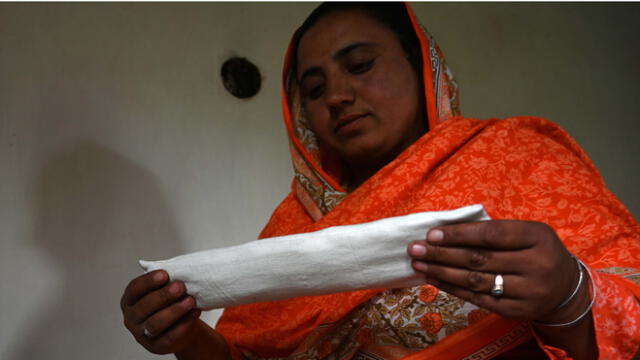 Hajra Bibi, mujer pakistaní, sostiene una compresa sanitaria que está haciendo con una máquina de coser en su casa en la aldea de Booni en Chitral.