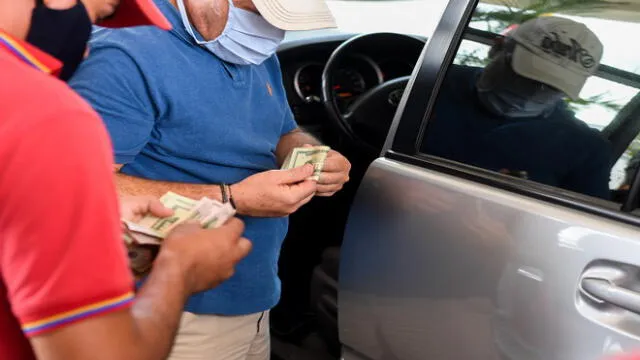A man wearing a face mask pays at a gas station in Caracas on June 1, 2020 amid the Covid-19 coronavirus pandemic. - Venezuela will increase fuel prices in June, President Nicolas Maduro said on Saturday, putting a limit on state subsidies that for decades had allowed citizens to fill their gas tanks virtually for free. (Photo by Federico PARRA / AFP)