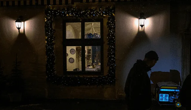 Un hombre se para junto a un generador de energía que abastece a un restaurante durante un apagón en la ciudad de Lviv, en el oeste de Ucrania. Foto: AFP