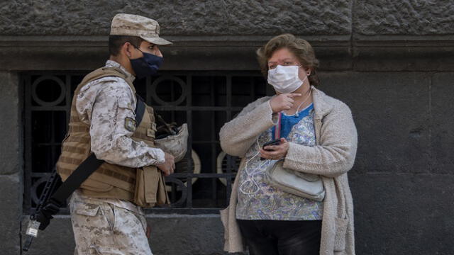 A soldiers and a woman wear face masks against the spread of coronavirus as they remain at a checkpoint at Plaza de Armas square in Santiago, Chile, May 06, 2020. - Chile's health authorities tightened mandatory confinement measures in Santiago on Wednesday, in the face of an increase in coronavirus cases, totaling 23,048 infected and 281 deaths in the country. (Photo by Martin BERNETTI / AFP)