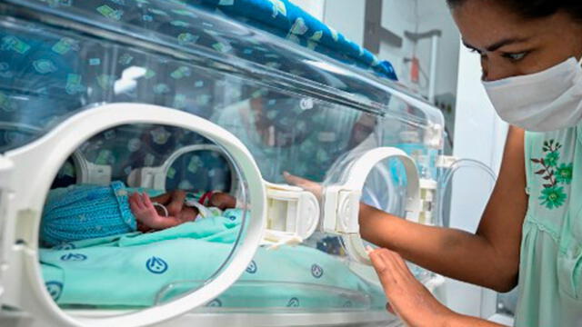 Diana Paola Angola, quien se recuperó del nuevo coronavirus, COVID-19, acaricia a su hijo Jefferson en la sala neonatal de la Clínica Versalles. Foto: AFP/ Luis Reboyo.
