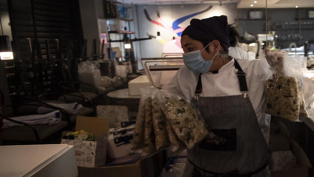 An assistant of Chilean chef Carolina Bazan, prepares food to be vacuum packed at her restaurant 'Ambrosia', in Santiago, on August 12, 2020. - Bazan prepares lunches for low-resource families affected by the pandemic as part of the "Comida para todos" (Food for All) project. Various initiatives multiplied during the months of the pandemic to alleviate hunger in Chile: soup kitchens are reproduced in the poorest neighborhoods and also several restaurants, some gourmet, turned on their kitchens so that no one goes to bed without eating. (Photo by MARTIN BERNETTI / AFP)