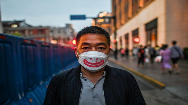 A man wearing a face mask walks along a street during a holiday on May Day, or International Workers' Day, in Shanghai on May 1, 2020. - With optimism and a heavy dose of caution, millions of Chinese hit the road or visited newly re-opened tourist sites on May 1 for an extended national holiday in a post-coronavirus confidence test. (Photo by Hector RETAMAL / AFP)