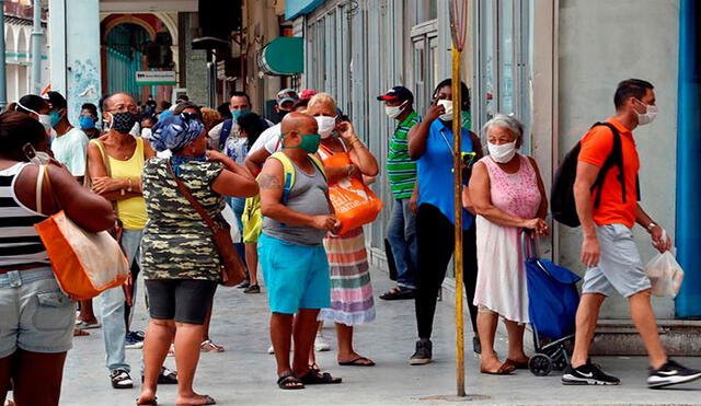 Varias personas con tapabocas hacen cola afuera de un centro comercial para comprar productos en La Habana (Cuba). Foto: EFE