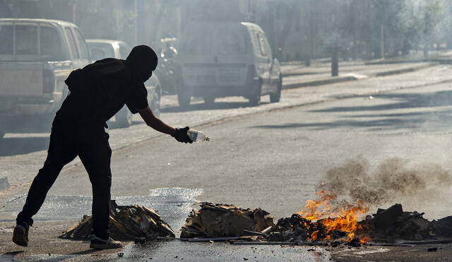 Un manifestante se prepara para encender una hoguera durante los enfrentamientos con la policía antidisturbios. Foto: AFP