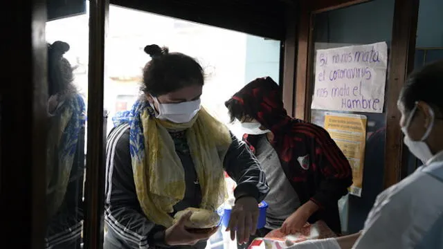 People receive a free meal at a community kitchen of the MRP (Movimiento Resistencia Popular) during the lockdown imposed by the government against the spread of the new coronavirus, COVID-19, at La Boca neighborhood in Buenos Aires, Argentina, on April 22, 2020. (Photo by JUAN MABROMATA / AFP)