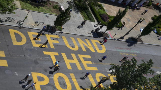 WASHINGTON, DC - JUNE 08: People walk down 16th street after Defund The Police was painted on the street near the White House on June 08, 2020 in Washington, DC. After days of protests in DC over the death of George Floyd, DC Mayor Muriel Bowser has renamed that section of 16th street "Black Lives Matter Plaza".   Tasos Katopodis/Getty Images/AFP
