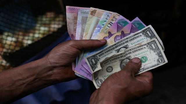 A market trader shows different currency notes in Caracas on March 10, 2019, during the third day of a massive power outage which has left Venezuelans without communications, electricity and water. - The unprecedented power outage already left 15 patients dead and threatens to extend indefinitely, increasing distress for the severe political and economic crisis hitting the oil-rich South American nation. (Photo by Cristian Hernandez / AFP)
