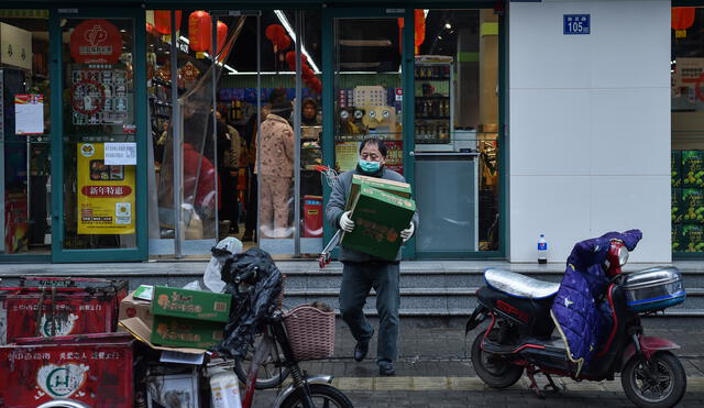 A man wearing a protective facemask carries boxes at a market in Wuhan on January 26, 2020, a city at the epicentre of a viral outbreak that has killed at least 56 people and infected nearly 2,000. - China on January 26 expanded drastic travel restrictions to contain an epidemic that has killed 56 people and infected nearly 2,000, as the United States, France and Japan prepared to evacuate their citizens from a quarantined city at the outbreak's epicentre. (Photo by Hector RETAMAL / AFP)