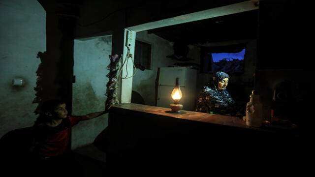 Una mujer palestina usa una lámpara de gas durante un corte de energía eléctrica después del cierre de la única planta de Gaza en medio de la tensión con Israel. Foto: MAHMUD HAMS / AFP.