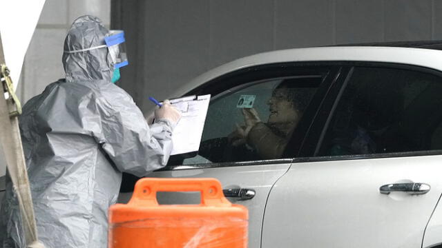 Workers in protective suits check id's of patients as they arrive by car to be tested for Coronavirus (COVID-19) at the State's First Drive Through COVID-19 Mobile Testing Center at Glen Island Park in New Rochelle, New York  March 13, 2020. - Governor Andrew M. Cuomo on March 13, 2020 opened the state�s first drive-through COVID-19 mobile testing center in New Rochelle. (Photo by TIMOTHY A. CLARY / AFP)