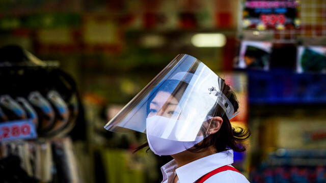 An employee wearing a face mask and a plastic shield, as a preventive measure against the spread of the COVID-19 coronavirus, waits for customers outside a shop in Sugamo district of Tokyo on Mau 24, 2020. - Prime Minister Shinzo Abe on May 21, 2020 lifted a state of emergency in several big cities in western Japan and hinted that the measure would be removed nationwide -- Tokyo and its neighbouring regions -- as early as next week. (Photo by Behrouz MEHRI / AFP)