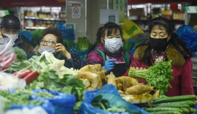 This photo taken on February 9, 2020 shows people wearing protective masks buying vegetables in Hangzhou in China's eastern Zhejiang province. - China consumer prices rose at their highest rate in more than eight years, official data showed February 10, with inflation more than expected on the back of Lunar New Year demand and a deadly virus outbreak. (Photo by STR / AFP) / China OUT