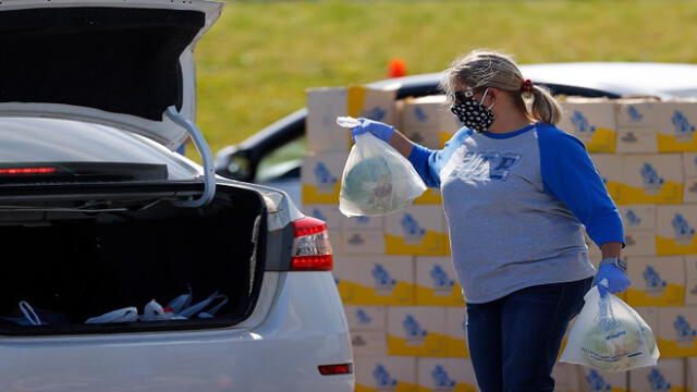 HAMPTON, GEORGIA - APRIL 17: A volunteer loads food into the back of a vehicle during a mobile market day at Atlanta Motor Speedway on April 17, 2020 in Hampton, Georgia. Atlanta Motor Speedway, Hampton Elementary, and the Atlanta Community Food Bank combined their efforts to provide food for all Hampton residents during this coronavirus (COVID-19) pandemic.   Kevin C. Cox/Getty Images/AFP