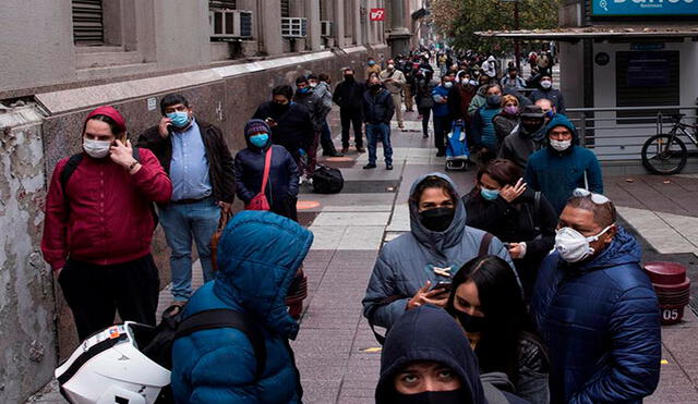 Un grupo de personas hace fila para acceder a un banco en el centro de Santiago, Chile.