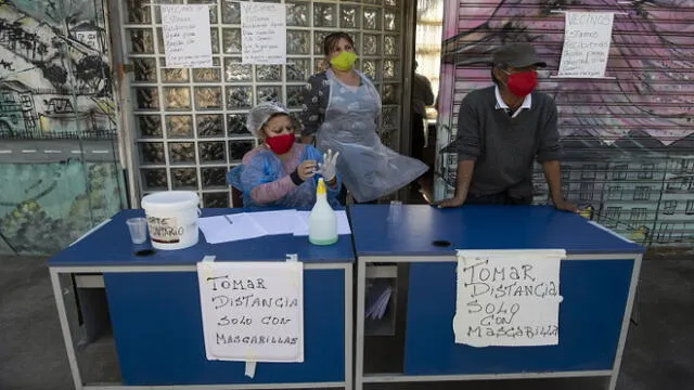 Volunteers wait, next to signs reading �Keep distance. Only with face masks�, for residents to come and take away lunches at a soup kitchen in La Pintana neighborhood, Santiago, on May 25, 2020, amid the new coronavirus pandemic. - Chile began Friday the delivery of 2.5 million boxes of basic products for the most vulnerable families amid protests due to food and job shortages caused by the measures imposed by the government against the new coronavirus pandemic. (Photo by MARTIN BERNETTI / AFP)