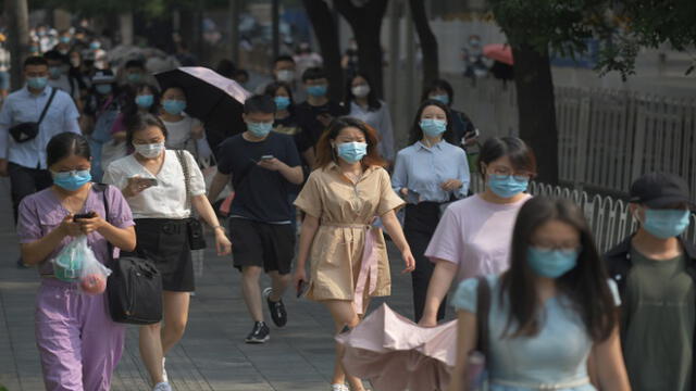 People wear masks as they walk to work in Beijing on June 28, 2020. - Beijing has partially lifted weeks-long lockdown imposed in the Chinese capital to head off a feared second wave of coronavirus infections after three million samples were taken in two weeks, officials said. Dozens of residential compounds across the city were shut down, with authorities rolling out a mass testing campaign to root out any remaining cases. (Photo by GREG BAKER / AFP)
