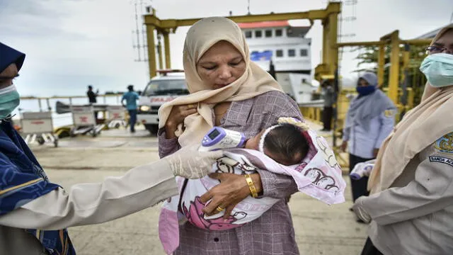 A health officer checks the body temperature of passengers, amid the COVID-19 coronavirus pandemic, as they get off a ferry at Ulee Lheue port in Banda Aceh on May 26, 2020. (Photo by CHAIDEER MAHYUDDIN / AFP)
