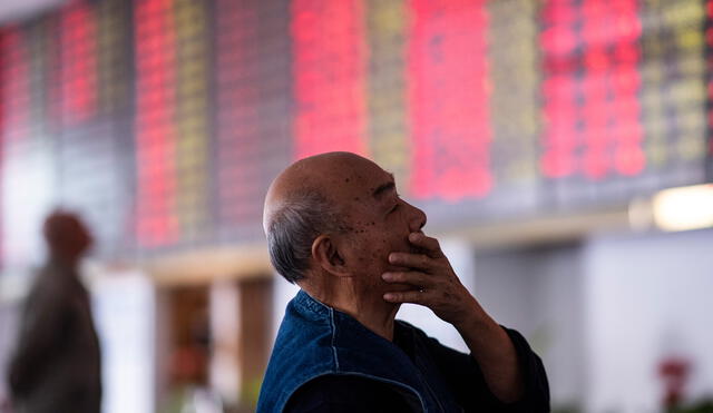 An investor looks at an electronic board showing stock information at a brokerage house in Shanghai on October 15, 2018. - Asian stocks started the week on the back foot on October 15, with investors still in gloomy mood after several days of market turbulence sparked by trade rows and a spat over the US central bank. (Photo by Johannes EISELE / AFP)