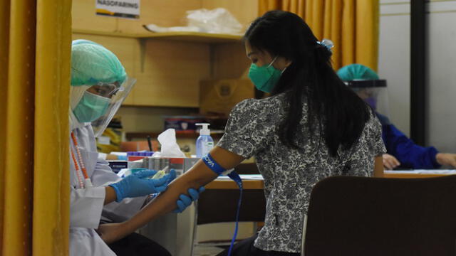 This photo taken on August 6, 2020 shows a volunteer (R) having blood samples taken before she receives COVID-19 coronavirus vaccine as part of a clinical trial on 1,620 volunteers, at the Padjadjaran University educational hospital in Bandung, West Java. (Photo by TIMUR MATAHARI / AFP)