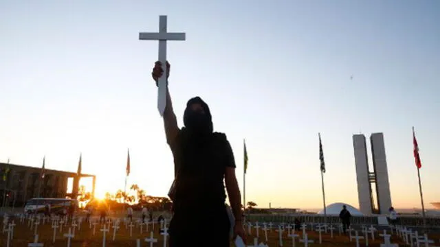 Un manifestante levanta una cruz durante una protesta contra el presidente brasileño Jair Bolsonaro y en honor a las personas que murieron por la COVID-19. Foto: AFP.